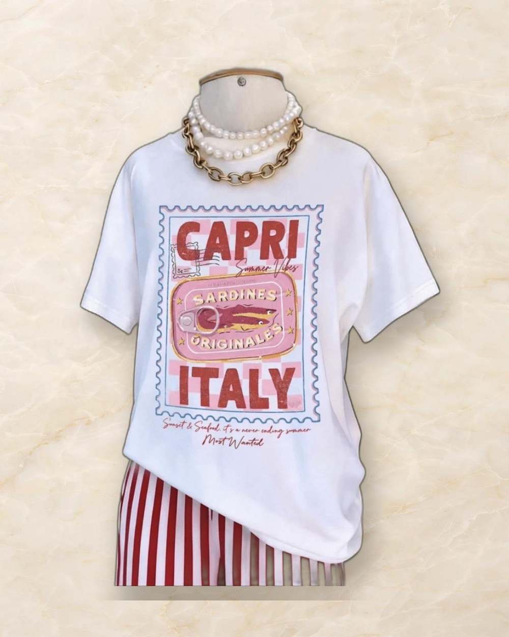 Franela blanca con estampado 'CAPRI ITALY' y sardinas., aislado sobre mármol marfil