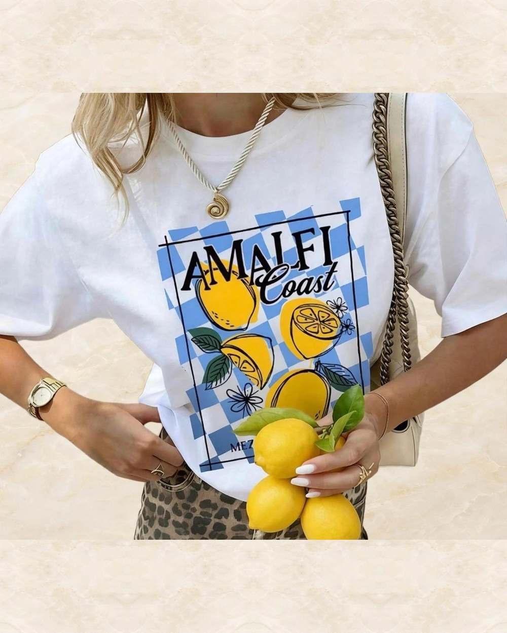 Franela blanca con estampado 'AMALFI Coast' y limones., aislado sobre mármol marfil