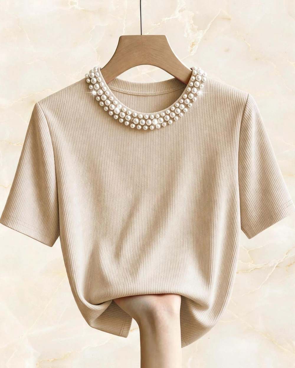 Blusa beige cuello perlas, aislado sobre mármol marfil
