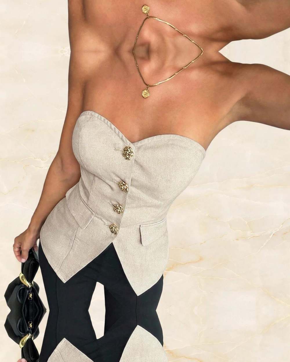 Top strapless beige botones dorados, aislado sobre mármol marfil