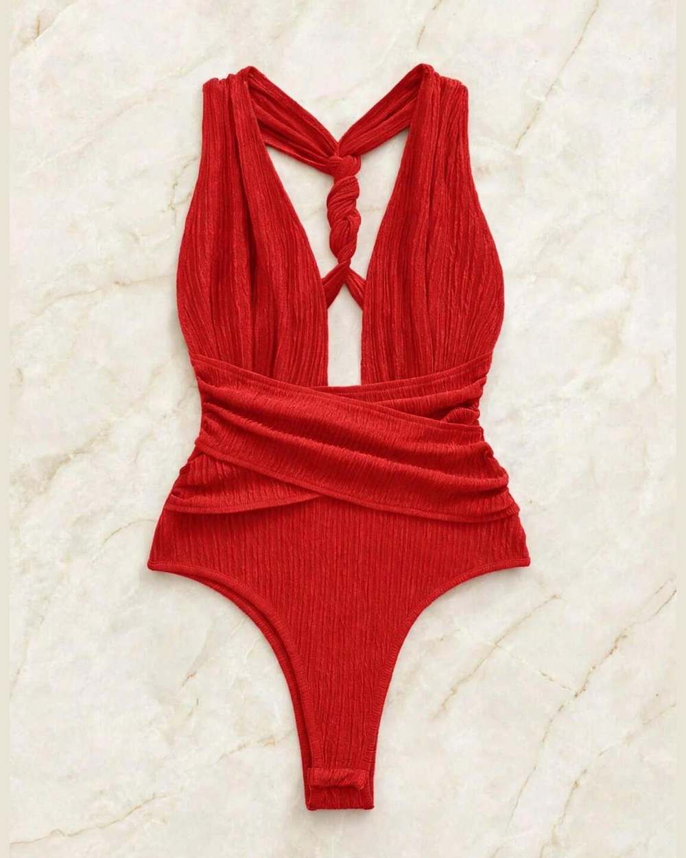 Body rojo acanalado con tiras cruzadas y nudo en la espalda, aislado sobre mármol marfil