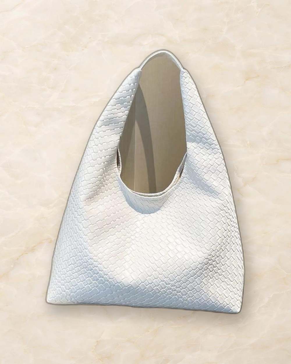 Cartera blanca tipo hobo de tejido., aislado sobre mármol marfil