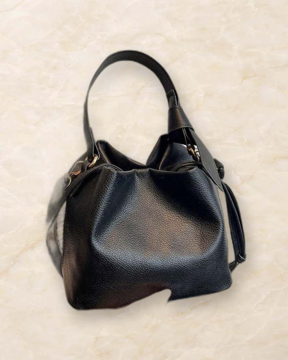 Cartera negra tipo bucket con detalle MILAN., aislado sobre mármol marfil