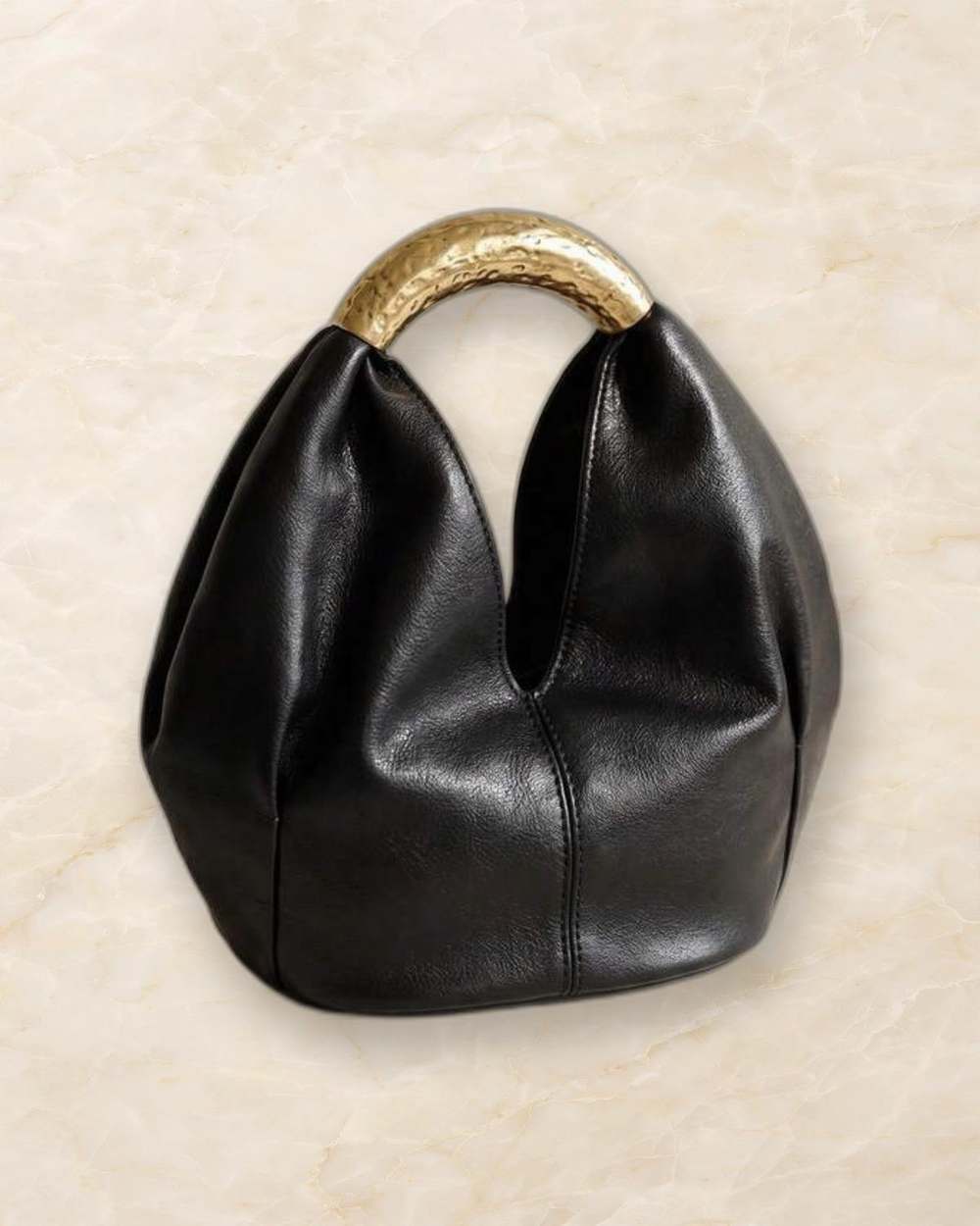 Cartera negra con asa dorada martillada., aislado sobre mármol marfil