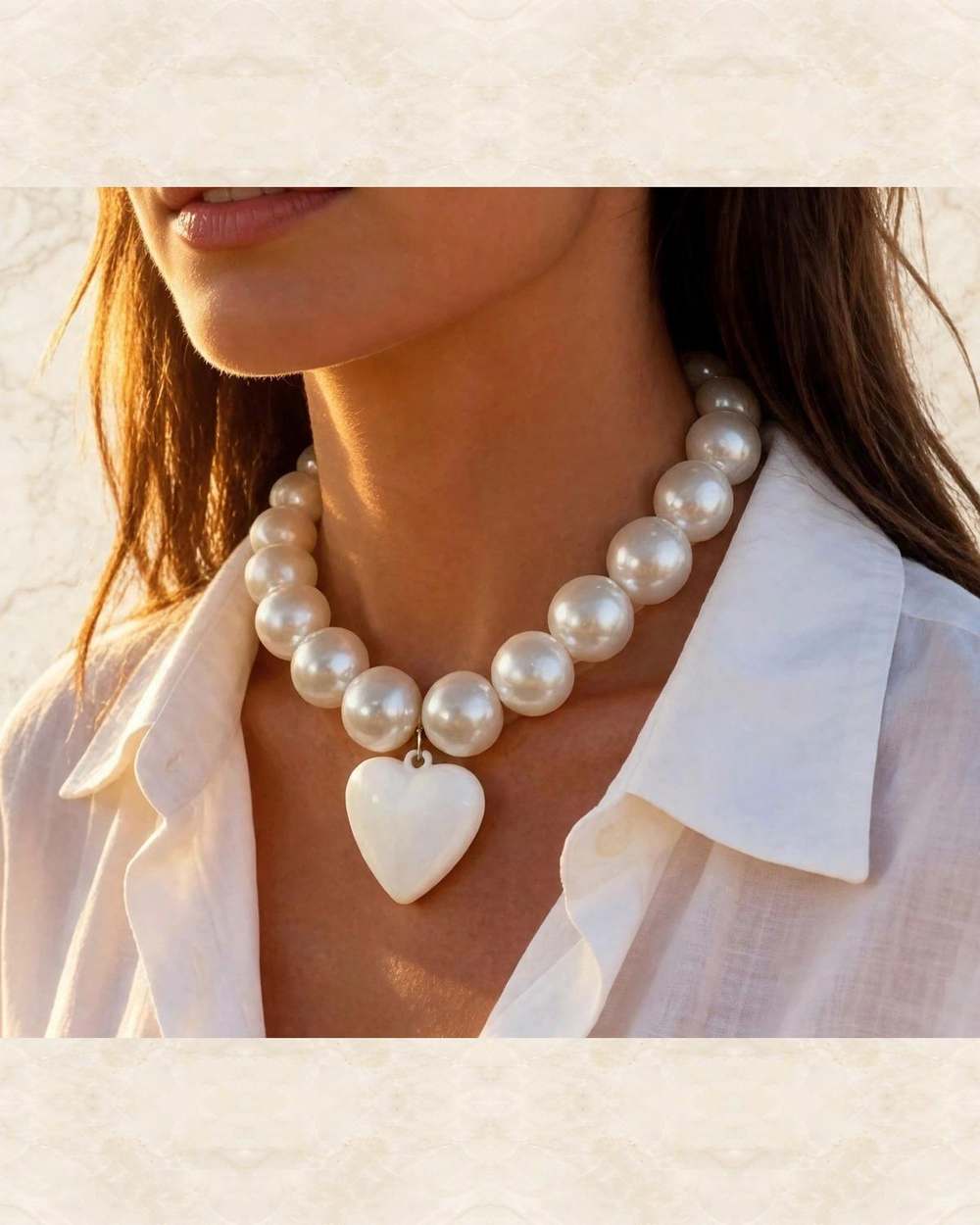 Collar de perlas con dije de corazon blanco., aislado sobre mármol marfil