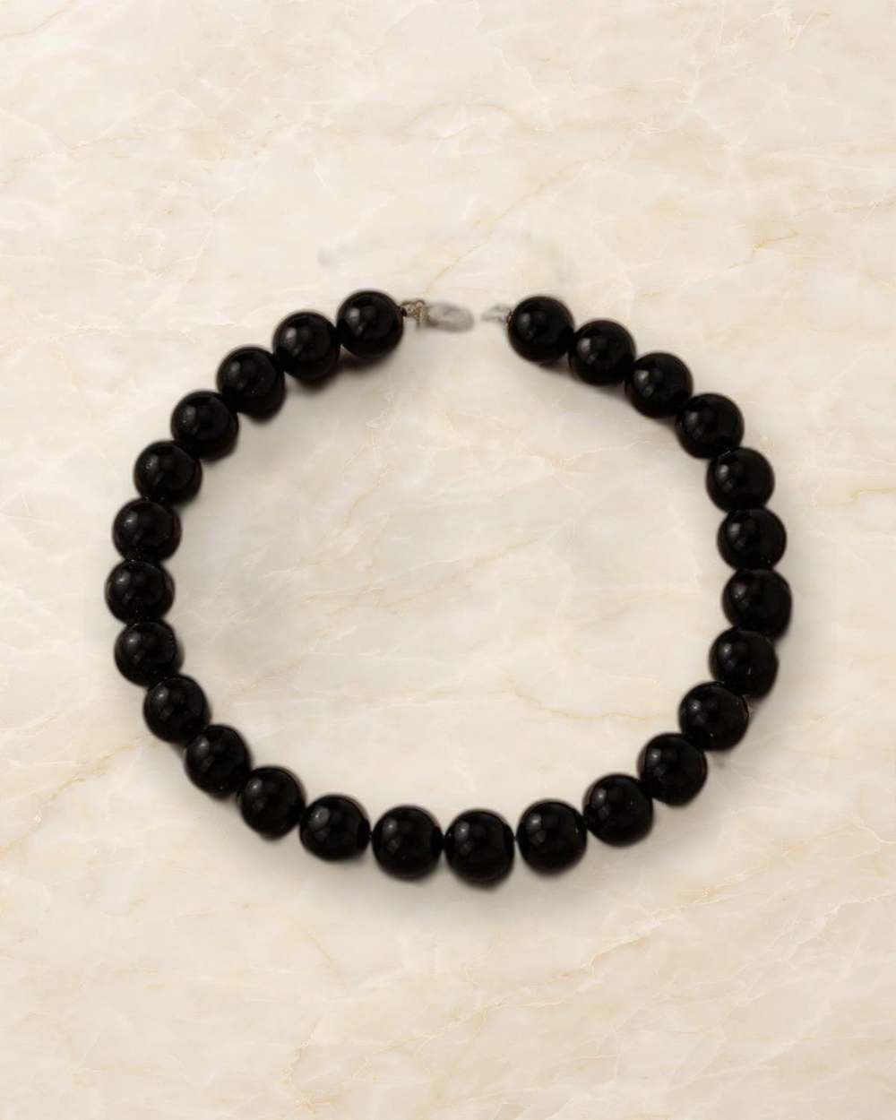 Gargantilla de perlas negras grandes con extensor dorado., aislado sobre mármol marfil