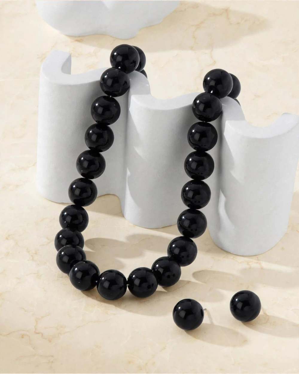 Set de collar de perlas negras con zarcillos de perla negra a juego., aislado sobre mármol marfil