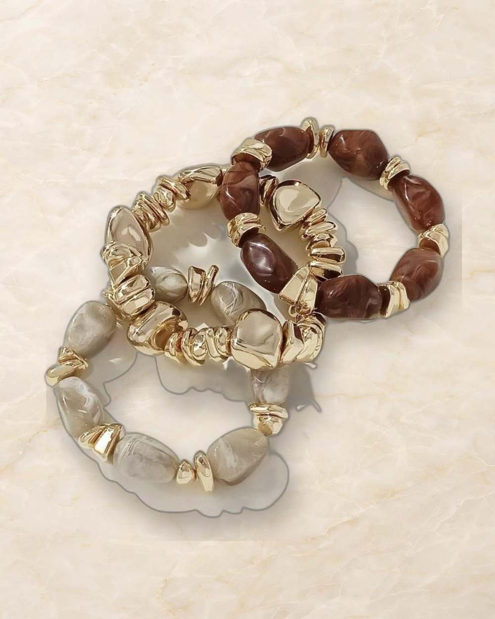 Set pulseras bangas marmol doradas, aislado sobre mármol marfil