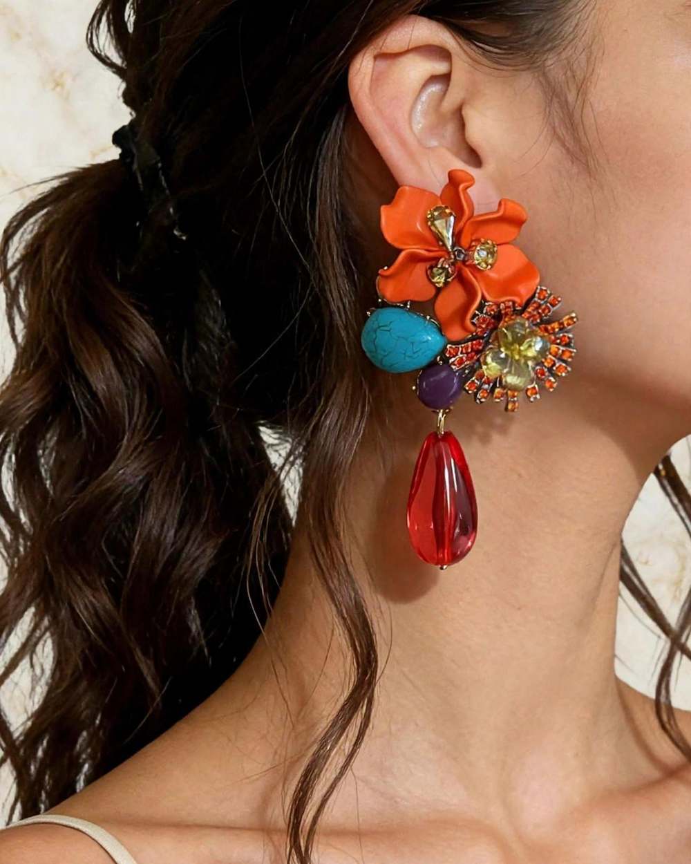 Modelo con zarcillo de flor naranja con piedras turquesa/morada y gota roja