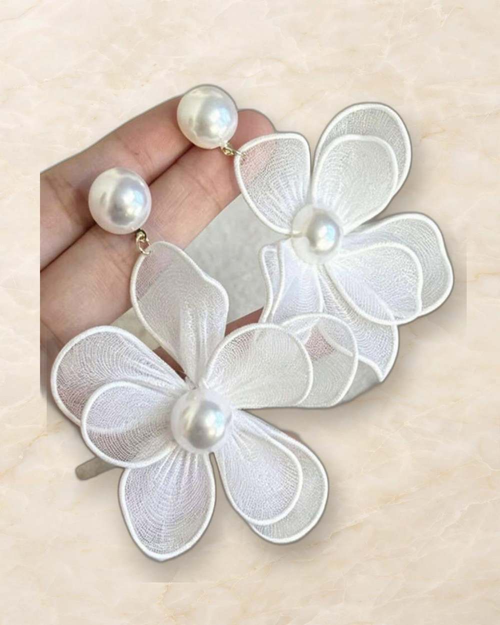 Zarcillos de flor con perlas., aislado sobre mármol marfil