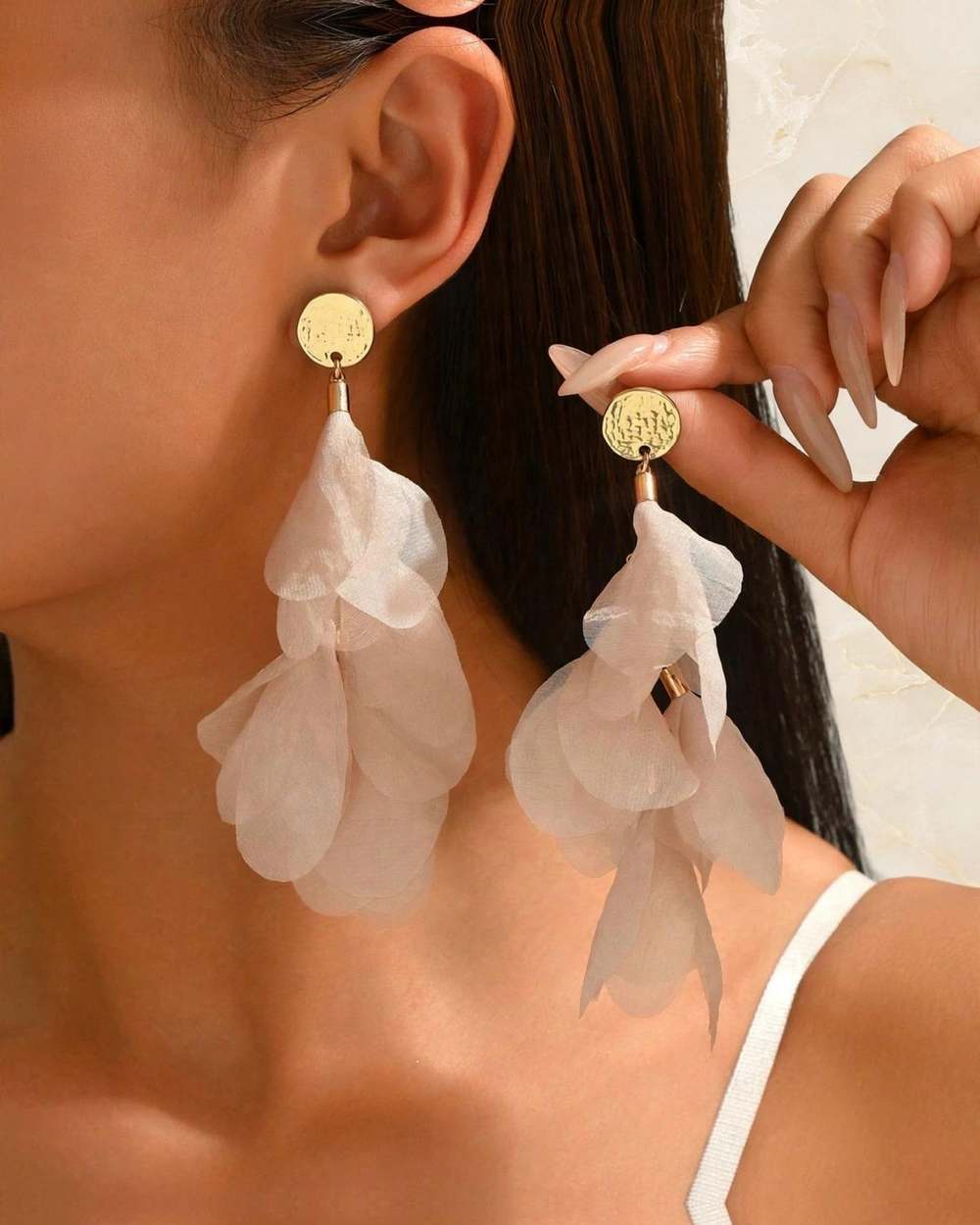 Zarcillos cascada petalos beige, aislado sobre mármol marfil